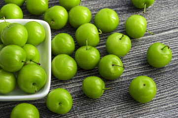 Green sour plums in the plate, plum pictures on the white ground,
Quality and natural life-giving green sour plums

