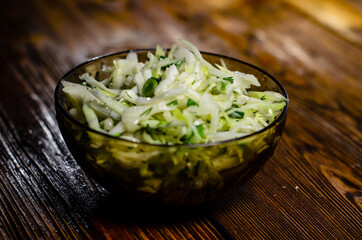 Salad with the cabbage and green onion on wooden table
