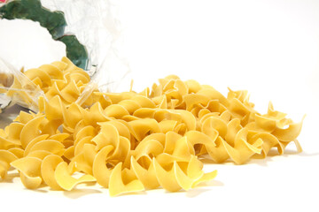 Raw yellow egg noodles spilling from bag. Isolated.