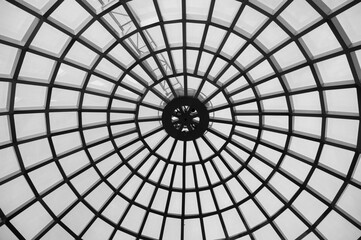 Transparent glass dome of a modern hotel. Metal frame frame, glass through which the blue sky is visible and illuminates the lobby of the hotel or business center.
