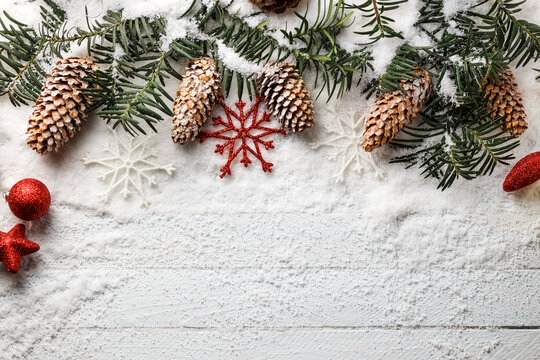 Snowy christmas background with fir branch and pine cones.