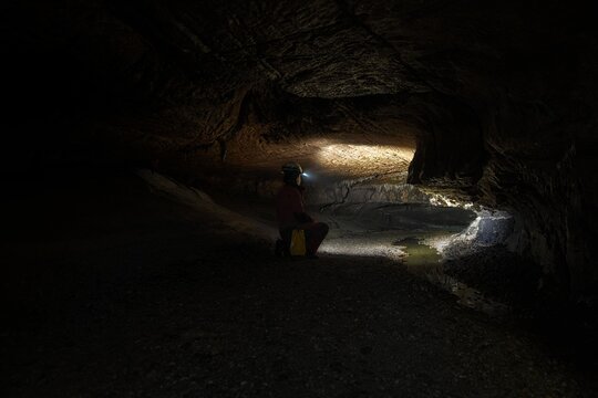 Woman With Headlamp Inside Cave
