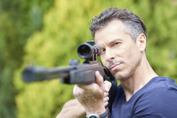 Fototapeta na wymiar Aiming at a target. Shot of a man with airgun practicing at the shooting range. 