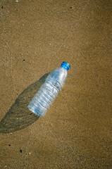 Fototapeta na wymiar Plastic bottle from drinking water as rubbish in the sand. The concept of environmental pollution by tourists and vacationers.
