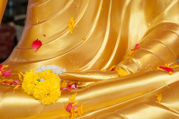 Close up hand part of golden Buddha statue with flower.