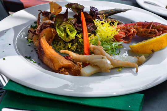 Verschiedene gegrillte Fischsorten auf einem wei&szlig;en Teller