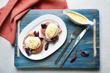 Tasty eggs Benedict with sauce on plate