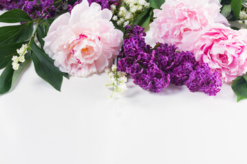Floral borders of fresh flowers - lilac, peonies and lilly of the walley flowers on white background