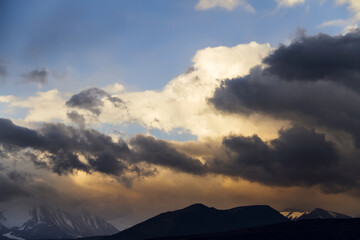 Altai Ukok the sunset over the mountains in cloudy cold weather. Wild remote places, no one around. Rain clouds over the mountains