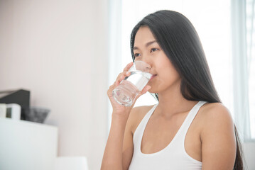 Asian woman drinking water at her bedroom.