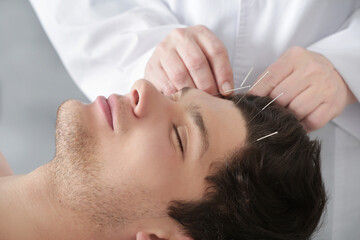 Young man undergoing acupuncture treatment in salon