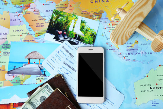 Composition with smartphone, passports and tickets on world map background