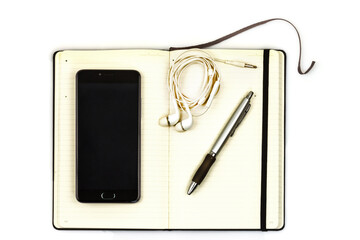 Smart phone with black blank display, pen, sheet of paper, notebook, earphones