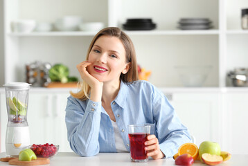 Beautiful woman with glass of fresh juice in kitchen