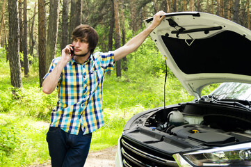 A sad man is waiting for help and calling the support service because his car broke down