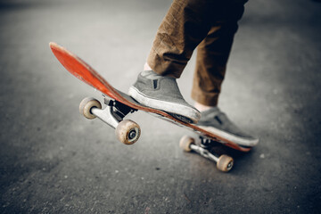 Close-up of a male guy on a skateboard doing trick kicks in shoes. The concept of doing street sports skateboarding. Sunset, toning pictures. © Parilov