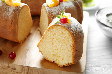 Sliced delicious yogurt cake with fruits and berries on wooden cutting board