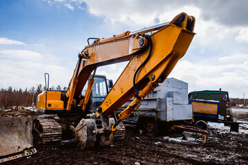 Yellow excavator on caterpillars on industrial site. Concept equipment for the construction of roads and houses.