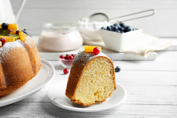 Sliced delicious yogurt cake with fruits and berries on white plate