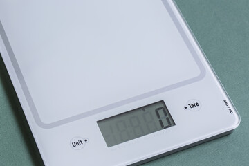 Empty digital kitchen scale on green paper background.