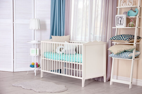 Interior of light cozy baby room with crib and bedding