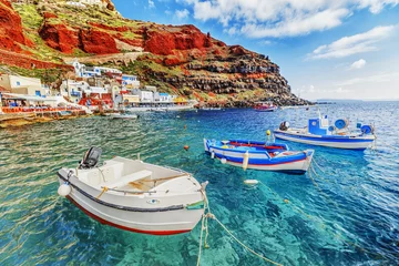 Fototapeten Fishing boats over clear turquoise water of Aegean sea at Old port Amoudi of Oia village at Santorini island, Greece © Feel good studio