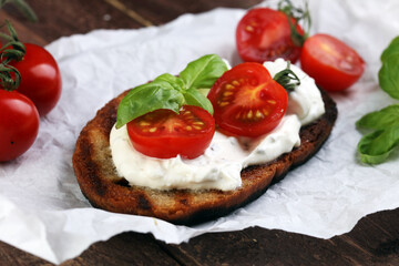 Bread with cream cheese and tomato for lunch table. Sharing antipasti on party or summer picnic time over wooden rustic background.