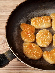 Chicken nuggets with sesame seeds on a frying pan