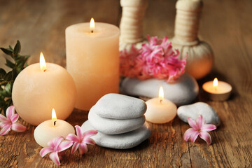 Fototapeta na wymiar Beautiful spa composition with stones, flowers and candles on wooden background
