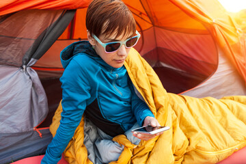 Girl with a phone in a sleeping bag.