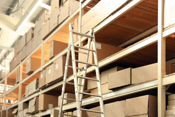 Ladder and boxes with goods in wholesale warehouse