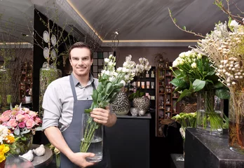 Tuinposter Bloemenwinkel Handsome florist in flower shop