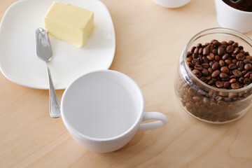 Composition with empty cup, coffee and butter on wooden table