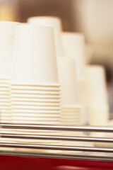 Rows of upside down white cups of cardboard for beverages, disposable tableware for caffee, tee, abstract nonexistent logo. Coffe to go, fast food, catering. Vertical