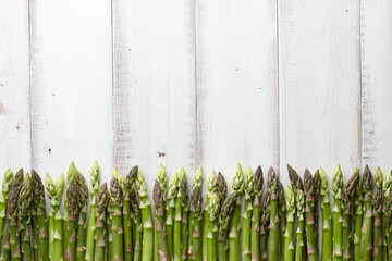 Fresh green asparagus in a row on white wooden background, copyspace