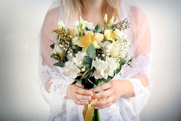 Beautiful bride holding bouquet with  freesia flowers on white background