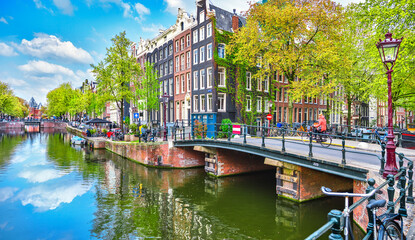 Bridge over channel in Amsterdam Netherlands houses river Amstel - obrazy, fototapety, plakaty