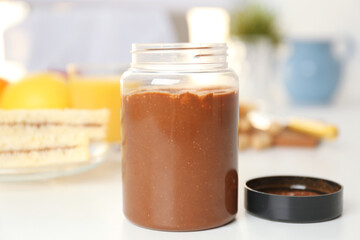 Delicious peanut butter in jar on kitchen table