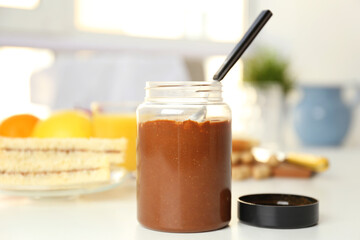 Delicious peanut butter in jar on kitchen table