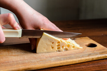 Slicing cheese on a wooden board.
