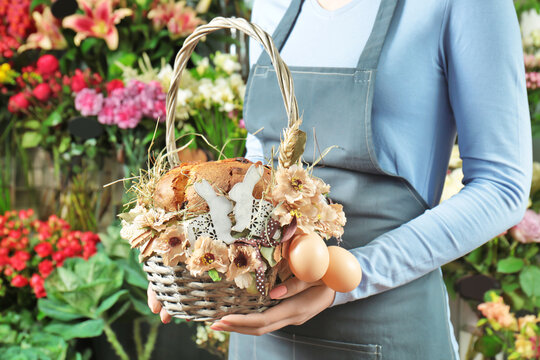 Woman holding Easter wicker basket with traditional cake in flower shop