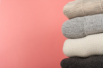 Knitted wool sweaters. Pile of knitted winter, autumn clothes on red,, wooden background, sweaters, knitwear, space for text