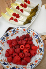 Tray with pickles, raspberries and endives and bowl with raspberries