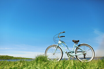 Obraz na płótnie Canvas Blue bicycle standing on grass near river
