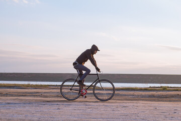 Alone rider on fixed gear road bike riding in the desert near river, hipster tourist bicycle rider pictures.