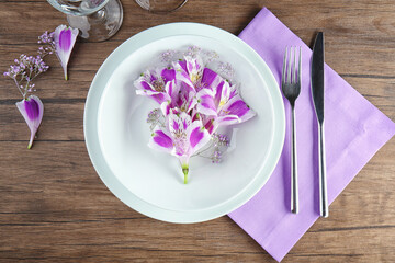 Beautiful festive table setting with floral decor on wooden surface