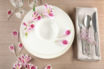 Beautiful festive table setting with floral decor on wooden surface