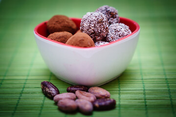 Chocolate truffles in a heart shaped bowl on a green background