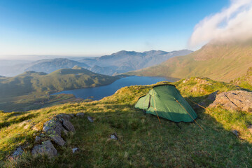 Wildcamping site with tent overlooking Stickle Tarn in the English Lake District on a sunny morning.