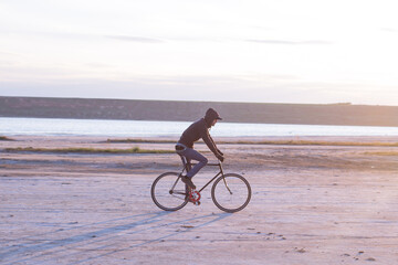 Alone rider on fixed gear road bike riding in the desert near river, hipster tourist bicycle rider pictures.